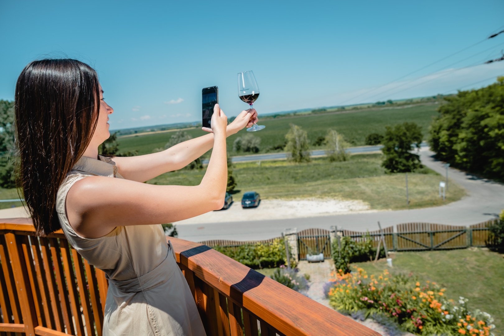 Woman takes photo of a glass of red wine with spectacular background