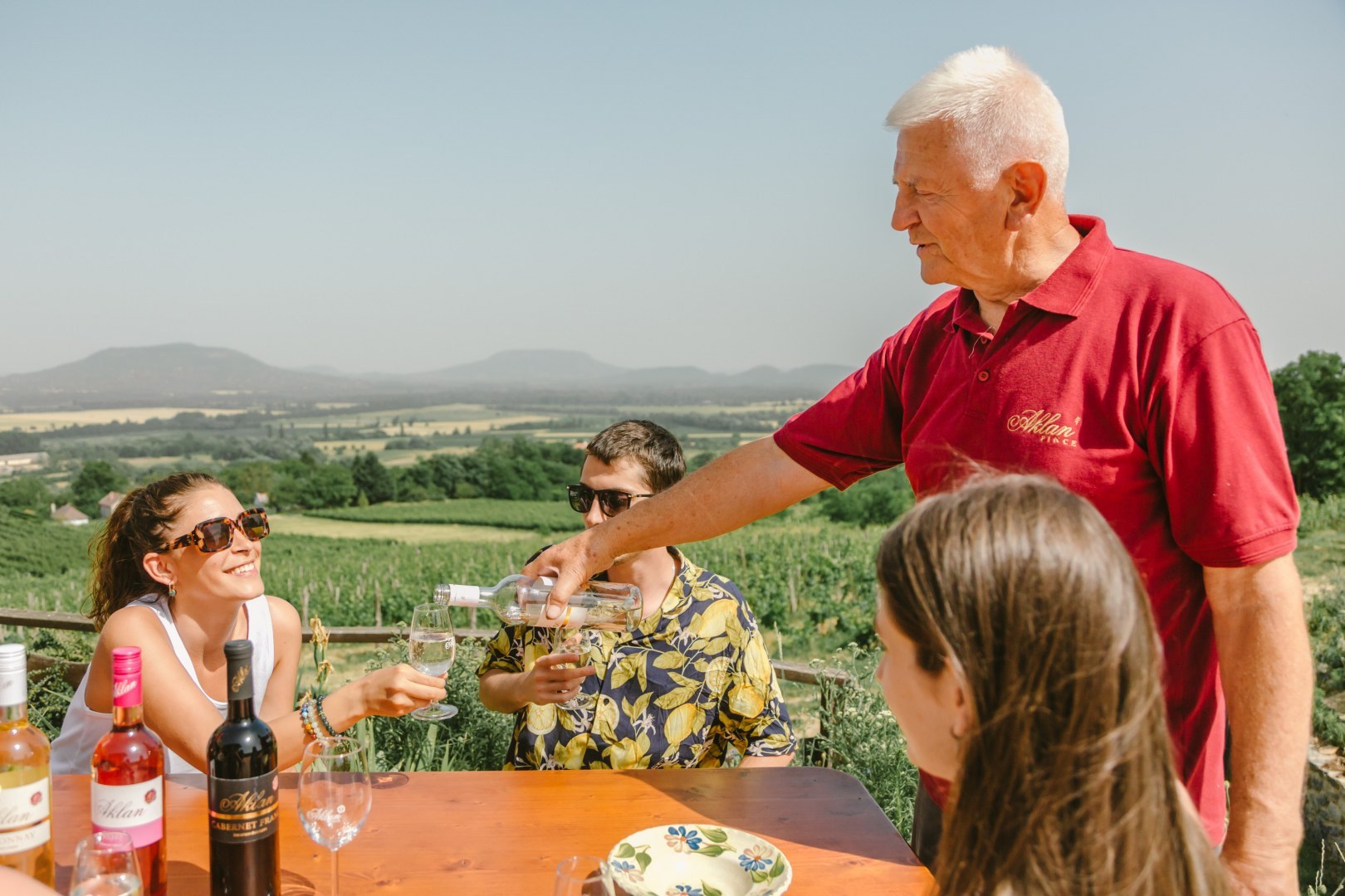 Senior pours wine for a young woman at Balaton